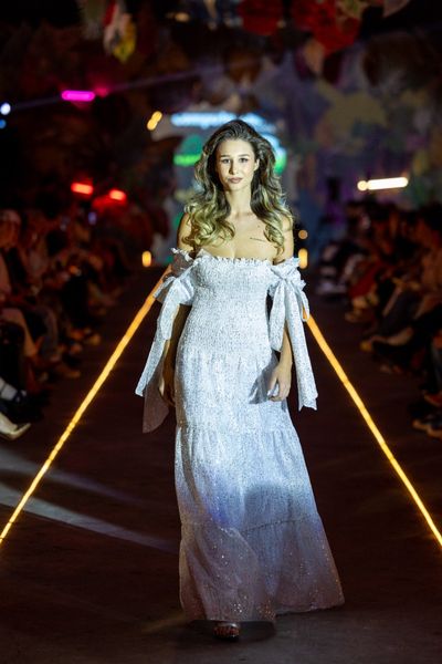 Rochie 74 – THE CREATION SNOW lunga, eleganta, alba, din material tip plasa accesorizat cu micropaiete argintii, fara maneci, cu umerii goi, cu funde pe umeri, gofrata in zona bustului si a taliei, 3 volane ample in partea de jos