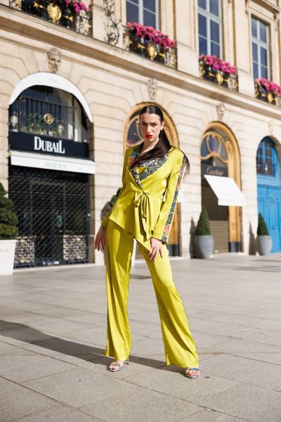 Costum GREEN SIMPHONY, format din sacou cu maneci lungi, pantaloni lungi si top, din satin elastic de culoare verde fistic, cu aplicatii din dantela de bumbac elastica, multicolora, si cristale multicolore aplicate manual