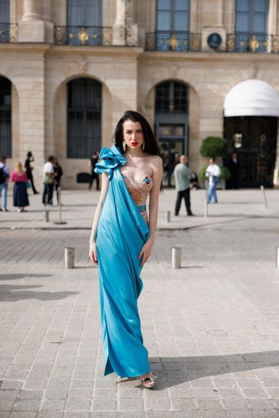 Rochie SOLARIA ANGEL lunga, fara maneci, cu corset, din tul bej cu broderie model floral, paiete si cristale, pe culorile bleu, orange, maro, peste care am aplicat de pe umarul drept pana jos tafta elastica bleu, dublura din satin elastic bej