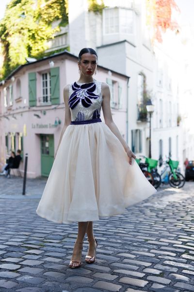 Rochie SOLARIA CREAM DESIRE midi, tip balerina, fara maneci, in partea de sus din tul cu micropaiete crem, cu aplicatii in forma de floare din catifea mov si cristale mov, cordon din stofa mov cu aplicatii manuale din cristale mov