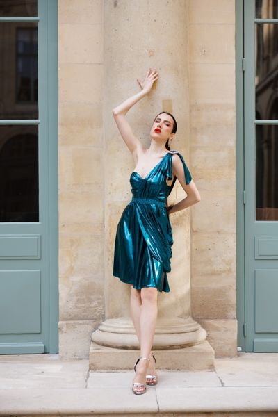 Rochie SOLARIA BLUE WAVES, scurta, fara maneci, asimetrica in partea de sus, pe un umar, dintr-o tesatura elastica cu pelicula albastru petrol lucioasa, cu o catarama din cristale multicolore pe un umar