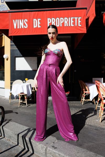 Costum SOLARIA PURPLE ANA este un set format din bustiera si pantaloni largi dintr-un material elastic violet cu irizatii, cu aplicatii din bumbac multicolor si paiete multicolore pe cupele bustierei